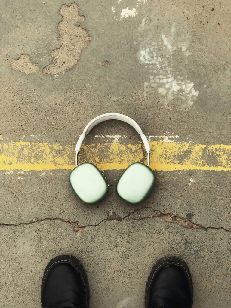 Overhead shot of wireless headphones on pavement with shoes visible, stylish and modern.